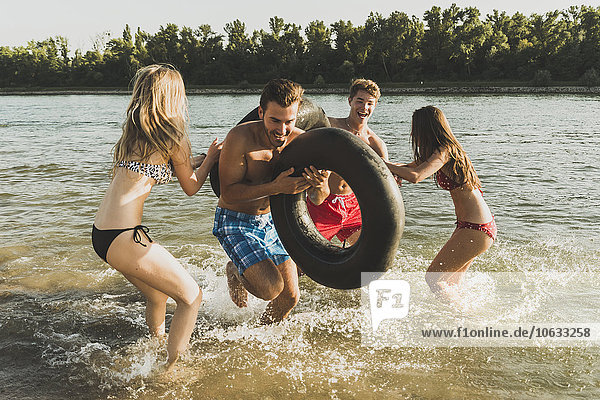 Playful friends with inner tubes in river