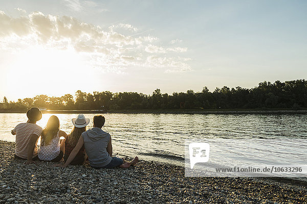 Freunde beim Sonnenuntergang am Flussufer entspannen