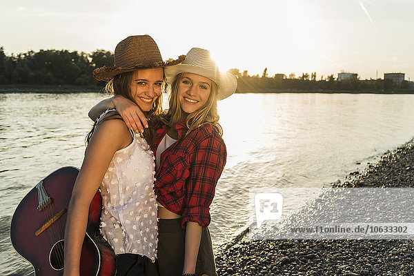 Two friends embracing at the riverside at sunset