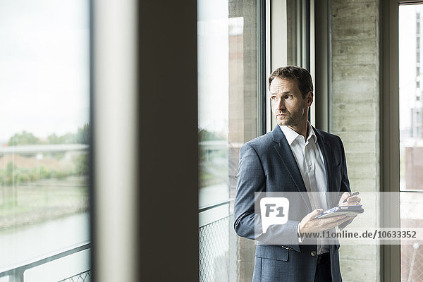 Porträt eines Geschäftsmannes beim Blick durchs Fenster