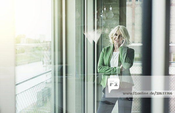 Portrait der blonden Geschäftsfrau beim Telefonieren mit dem Smartphone