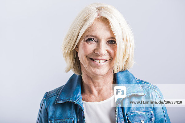 Portrait of smiling blond woman wearing blue leather jacket