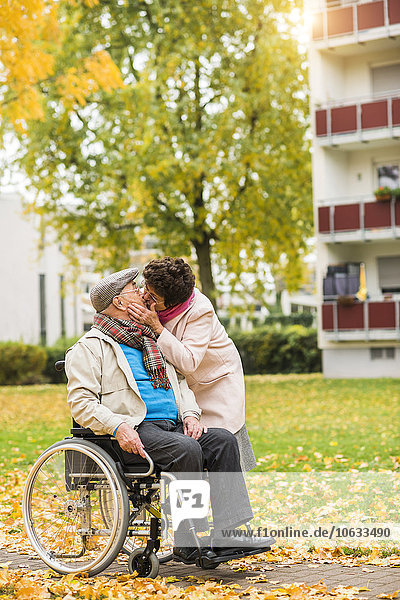 Seniorin küssend Ehemann im Rollstuhl