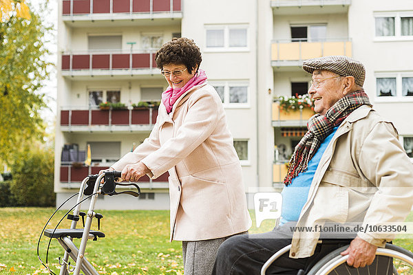 Seniorin mit Rollator und Senior im Rollstuhl im Herbst im Freien