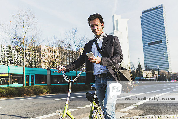 Deutschland,  Frankfurt,  Jungunternehmer in der Stadt mit dem Fahrrad,  per Handy