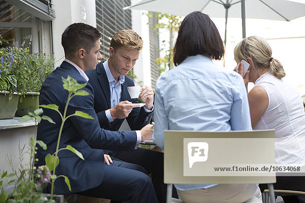 Vier Geschäftsleute sitzen am Tisch im Freien.
