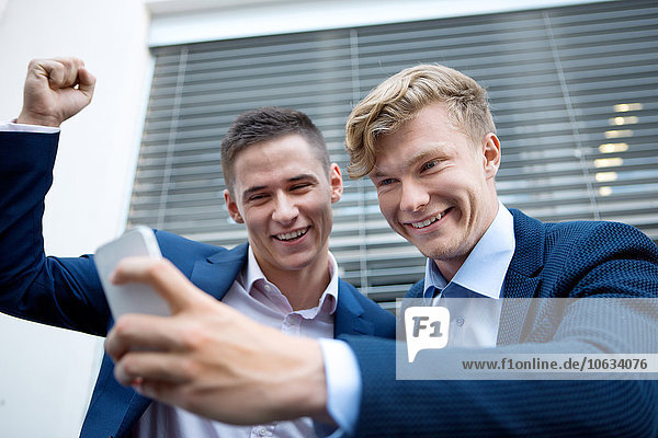 Two happy businessmen looking at cell phone
