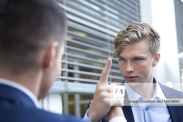 Serious businessman looking at colleague outdoors