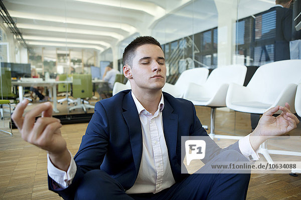 Young businessman meditating in office