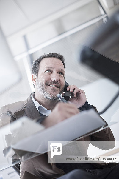 Smiling businessman talking on phone in office