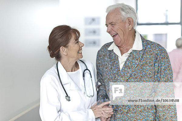 Arzt mit glücklicher älterer Patientin auf dem Krankenhausboden