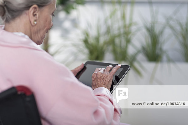 Elderly patient in wheelchair using digital tablet