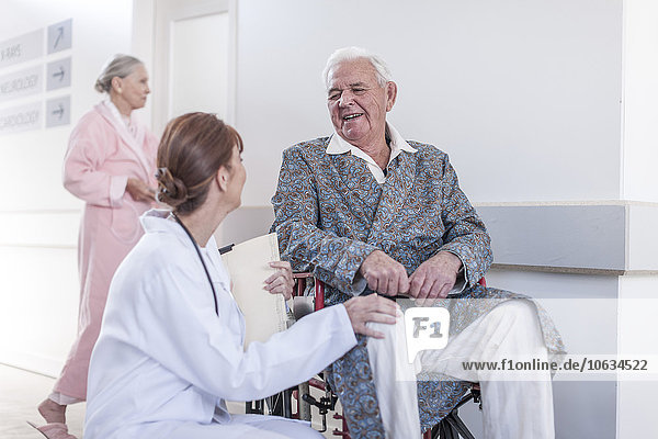 Doctor and smiling elderly patient in wheelchair