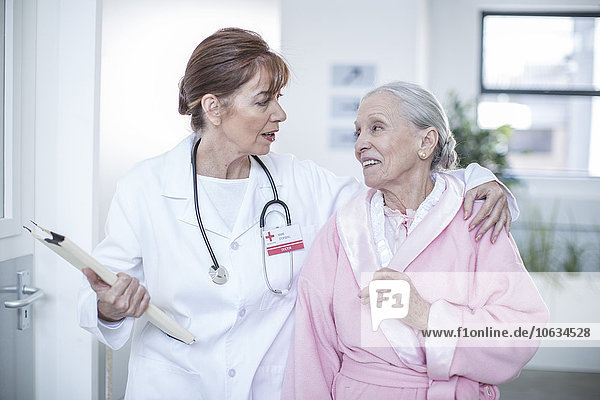 Arzt und lächelnder älterer Patient auf dem Krankenhausboden