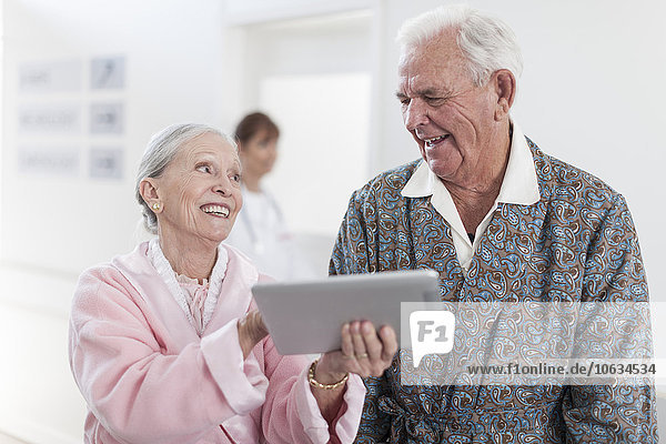 Arzt und lächelnder älterer Patient im Rollstuhl mit digitalem Tablett
