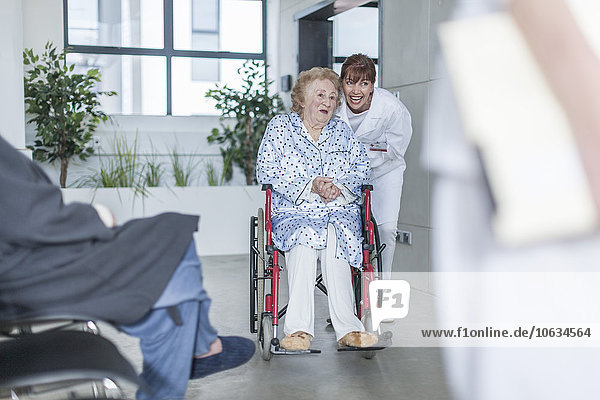 Doctor with elderly patient in wheelchair on hospital floor