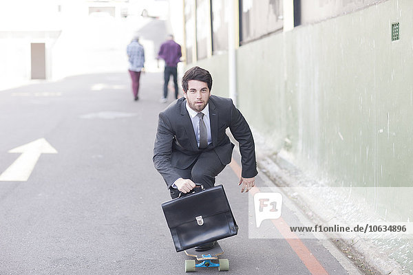 Geschäftsmann auf dem Skateboard auf der Straße
