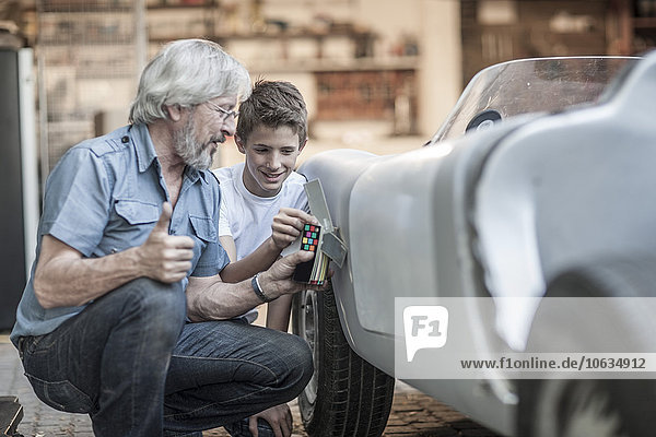 Grandfather and grandson restoring a car together