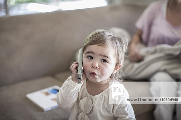 Kleines Mädchen mit einer Fernbedienung als Telefon