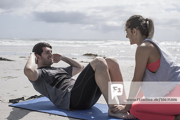 Young man and woman exercising on beach