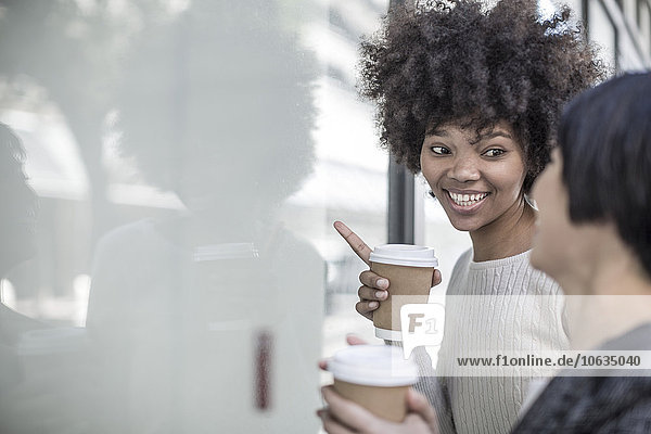 Zwei junge Frauen mit Kaffee im Schaufenster