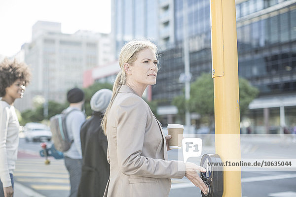 Woman waiting to cross a city street  pressing pedestrian crossing button