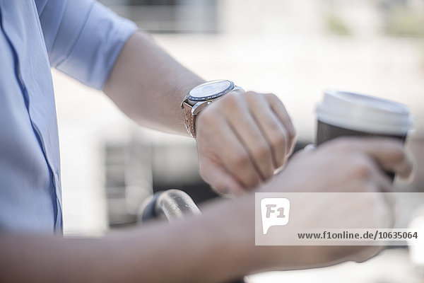 Junger Mann kontrolliert die Zeit schaut auf die Armbanduhr.