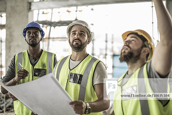 Bauarbeiter diskutieren Bauplan auf der Baustelle
