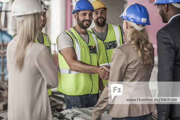 Bauarbeiter und Führungskraft beim Händeschütteln auf der Baustelle