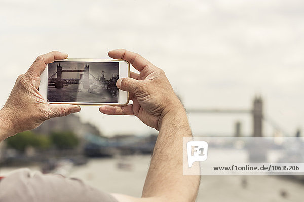 UK  London  man taking photo of Tower Bridge with his smartphone
