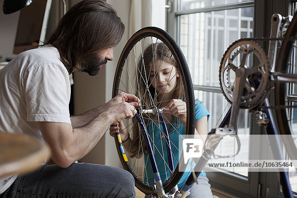 Vater und Tochter reparieren gemeinsam zu Hause das Fahrrad