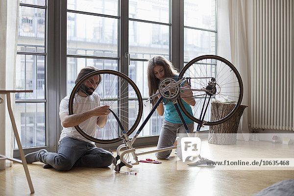 Vater und Tochter reparieren das Fahrrad gemeinsam zu Hause