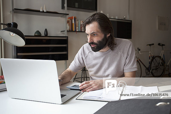 Mid adult man working on laptop at home