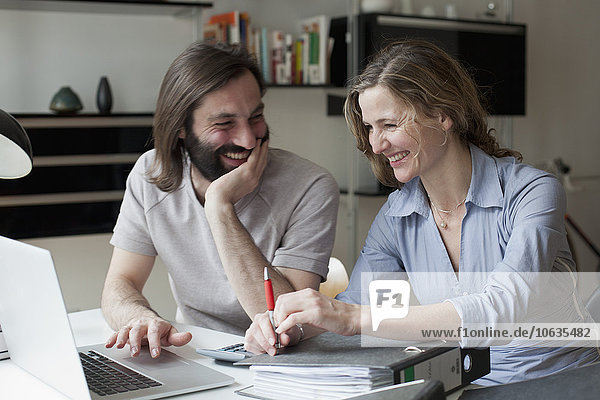 Happy couple using laptop while working from home