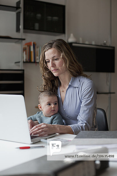 Frau mit Laptop beim Sitzen mit Baby Girl zu Hause