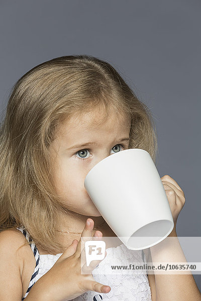 Süßes Mädchen trinkt Kaffee vor grauem Hintergrund