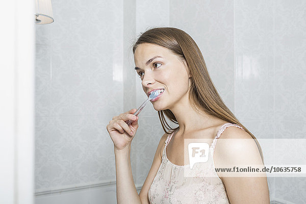 Porträt einer glücklichen Frau beim Zähneputzen im häuslichen Badezimmer