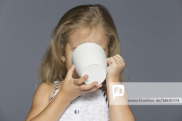 Mädchen trinkt Kaffee vor grauem Hintergrund
