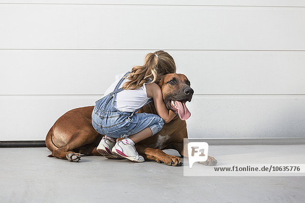 Mädchen umarmt Hund im Freien