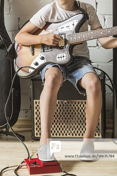 Niedriger Teil des Jungen  der zu Hause Gitarre spielt.