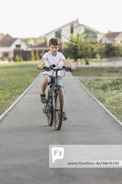 Junge Radfahren auf dem Fußweg