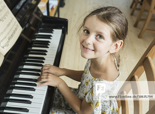 Hochwinkel-Porträt eines Mädchens  das zu Hause Klavier spielt