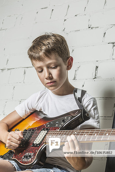 Junge spielt zu Hause Gitarre gegen Wand