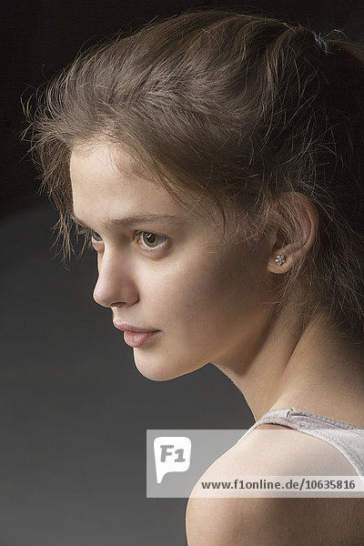 Close-up of thoughtful young woman looking away against gray background