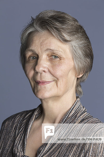 Porträt der lächelnden Seniorin vor violettem Hintergrund