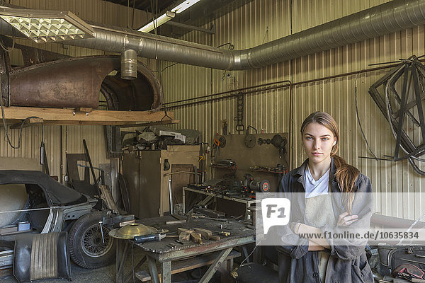 Portrait of confident female mechanic with arms crossed at repair shop