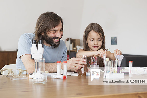 Vater und Tochter arbeiten zu Hause an einem Wissenschaftsprojekt