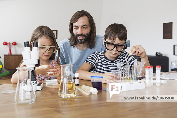 Father assisting children in doing school science project at home