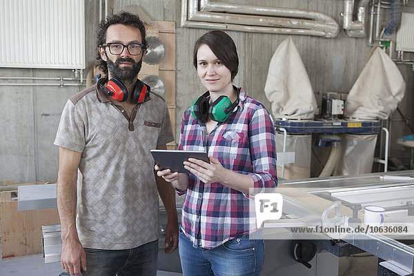 Porträt von selbstbewussten Schreinern mit digitalem Tablett in der Werkstatt