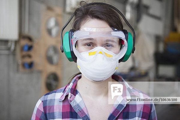 Porträt einer Schreinerin in Arbeitsschutzbekleidung in der Werkstatt